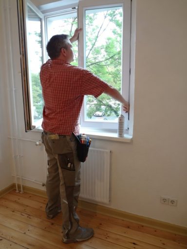 Fachgerechte Justierung eines Fensters Fachmann überprüft und stellt die Fenstermechanik bei Wartungsarbeiten ein